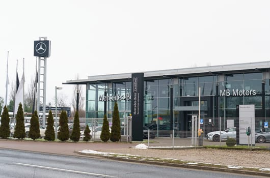 Poznan, Poland - January 25, 2023: Mercedes Benz car showroom, next to it behind a mesh fence are new cars.