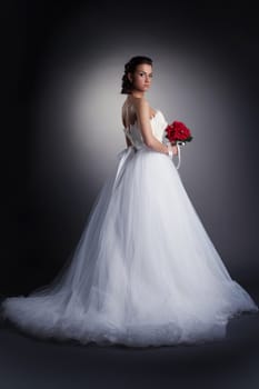 Gorgeous bride posing in elegant dress on dark background