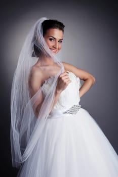 Portrait of smiling bride hiding behind veil, close-up