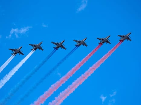 MOSCOW, RUSSIA - MAY 7, 2021: Avia parade in Moscow. Group of Russian fighters Sukhoi Su-25 with painted russian flag in the sky on parade of Victory in World War II in Moscow, Russia