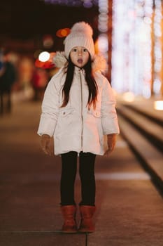 Cute scared lost little girl in a big city in the evening in winter. kid lost