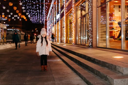 Cute scared lost little girl in a big city in the evening in winter. kid lost