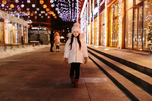 Cute scared lost little girl in a big city in the evening in winter. kid lost