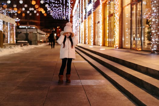 Cute scared lost little girl crying on the streets of big city in the evening in winter. kid lost