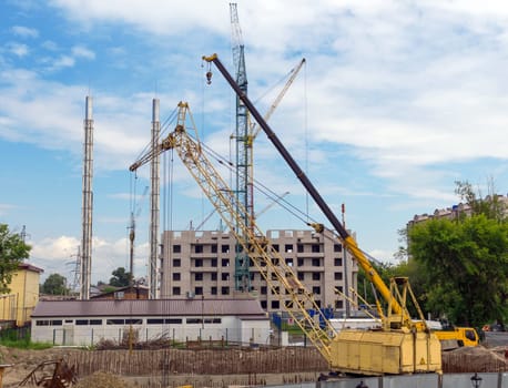 Tower cranes against blue sky, with clouds.