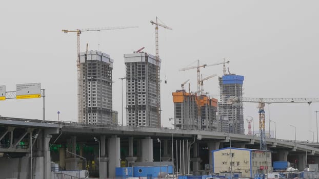 Many of cranes. Tower cranes against blue sky, with clouds.