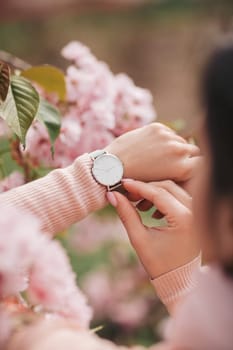 Stylish watch on woman hand on flower background. woman looking at her watch.