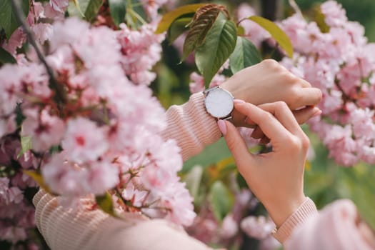 Stylish watch on woman hand on flower background. woman looking at her watch.