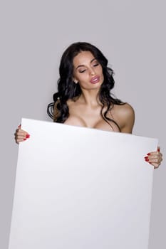 seductive naked brunette woman holding empty board. attractive sexy girl with blank board with copy space