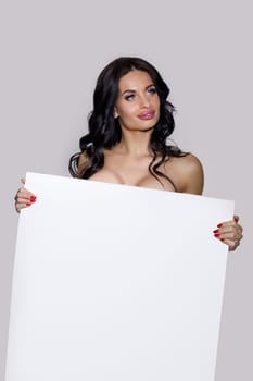 seductive naked brunette woman holding empty board. attractive sexy girl with blank board with copy space