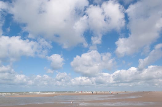 Clear blue sky and white dynamic clouds over the sea, view of the horizon, the bay of the sandy beach, residential buildings are visible in the distance, High quality photo