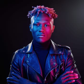 Futuristic neon lighting. Young african american man standing in studio with arms crossed.