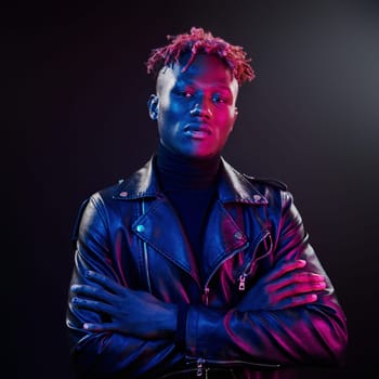 Futuristic neon lighting. Young african american man standing in studio with arms crossed.