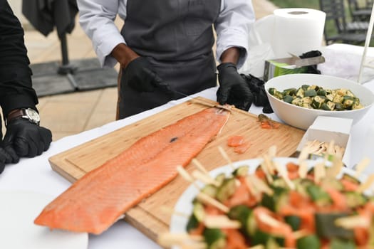 Cooks cut salmon fish at a wedding