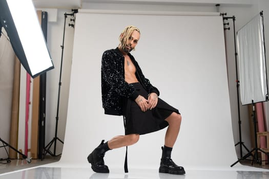 Full length gay man wearing women clothing dancing. Brazilian homosexual male wearing black skirt and boots posing in photo studio on white background. Bearded gay with make up