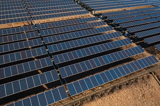 Long rows of photovoltaic panels at solar farm for converting energy of sun to electricity in concept of renewable energy and natural resources. Aerial view