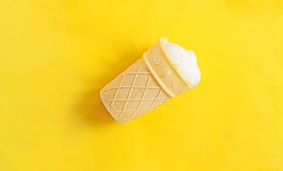 Vanilla ice-cream in a waffle cup on yellow background.