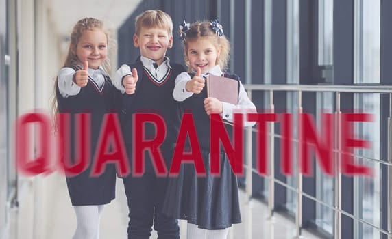 Red quarantine word. Group of kids in school uniform standing together indoors.