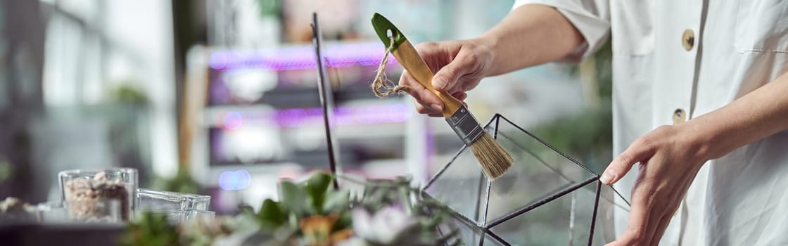 caucasian confident happy florist is working with composition made from glass stones and plants in botanic shop