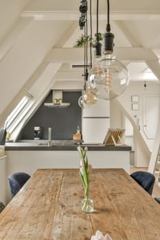 a wooden table and chairs in a room with an attic style ceiling above it, there is a light bulb hanging over the top