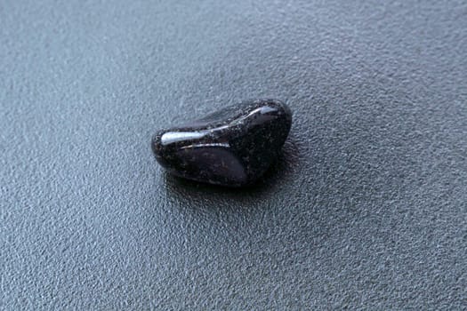 Close up of natural mineral from geological collection tumbled black onyx gem stone, black background