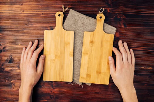 Wooden cutting board for two with a napkin on a wooden table, top view. Copy space for text