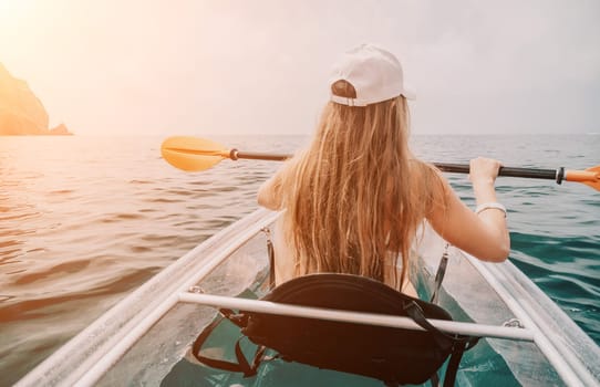 Woman in kayak back view. Happy young woman with long hair floating in transparent kayak on the crystal clear sea. Summer holiday vacation and cheerful female people having fun on the boat.