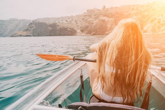 Woman in kayak back view. Happy young woman with long hair floating in transparent kayak on the crystal clear sea. Summer holiday vacation and cheerful female people having fun on the boat.