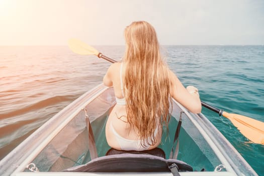 Woman in kayak back view. Happy young woman with long hair floating in transparent kayak on the crystal clear sea. Summer holiday vacation and cheerful female people having fun on the boat.