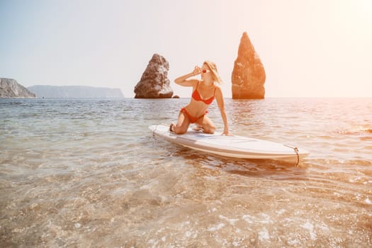 Close up shot of beautiful young caucasian woman with black hair and freckles looking at camera and smiling. Cute woman portrait in a pink bikini posing on a volcanic rock high above the sea