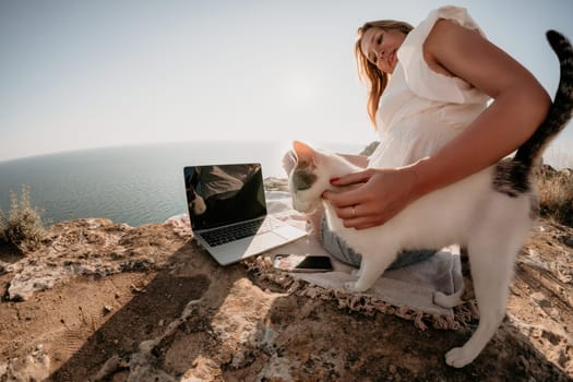 Woman sea laptop. Business woman in yellow hat working on laptop by sea. Close up on hands of pretty lady typing on computer outdoors summer day. Freelance, digital nomad, travel and holidays concept.