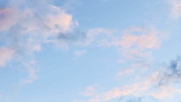 Background of blue sky with pale pink clouds at sunset