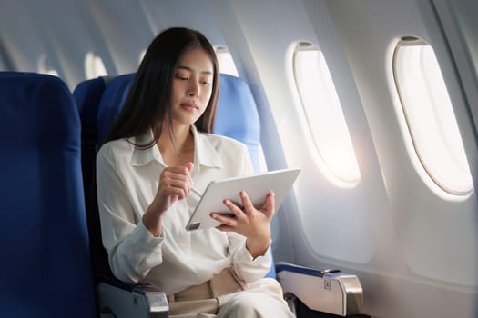 Beautiful Asian businesswoman working with digital tablet in aeroplane. working, travel, business concept.