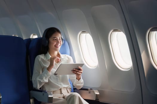 Beautiful Asian businesswoman working with digital tablet in aeroplane. working, travel, business concept.