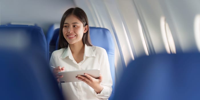 Beautiful Asian businesswoman working with digital tablet in aeroplane. working, travel, business concept.