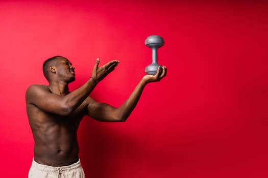 Portrait of happy african man with dumbbells over red and black background