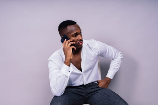 Handsome excited young african business man with a mobile phone isolated over gray background