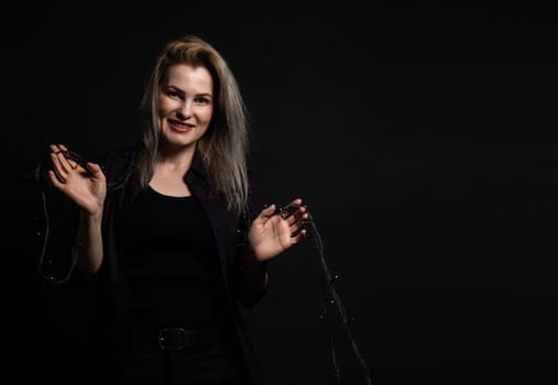 the sexy strict woman with makeup and a fashionable hairstyle poses in studio on black background