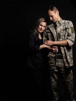 military man and his wife on a black background.