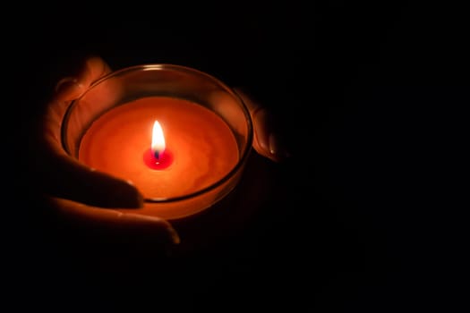 Close up of woman hand lighting candles in the dark night at home.