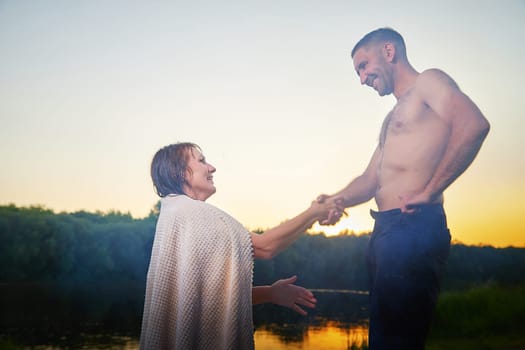 Happy Couple Outdoor relaxin and having fun on nature in the park in summer evening with smog and fog. Family or lovers have date and rest outdoors. Girl takes off jeans from man or guy