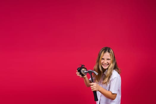 Kid girl holding hammer and alarm clock smiling with happy and cool smile on face. showing teeth.