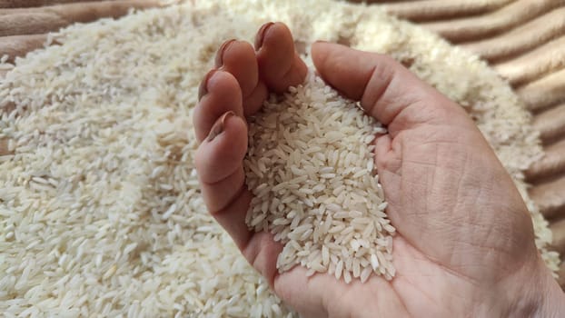 White cereals rice and hand of woman in it. Food for background and texture. Product and food which can be stored for a long time. Partial focus