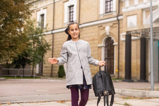 Preteen girl child with backpack outdoors. Pretty schoolgirl going home after class.