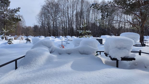 Ukrainian traditional cemetery in winter snow. Many of unmarked and faceless gravestones and crosses with forest in background. Graves in Russia after war