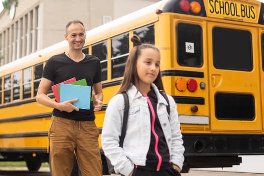 first day at school. father leads a little child school girl in first grade