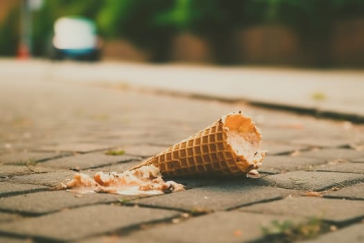 Melting ice cream cone drop upside down on the street in summer day. Selective focus, Soft focus.
