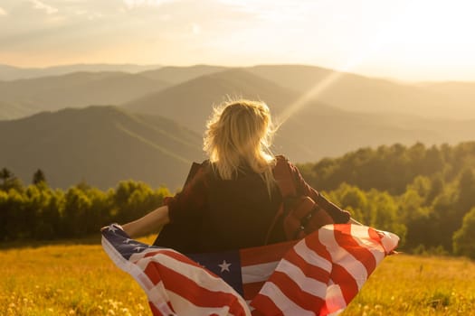 Young woman holding American flag on sky background.