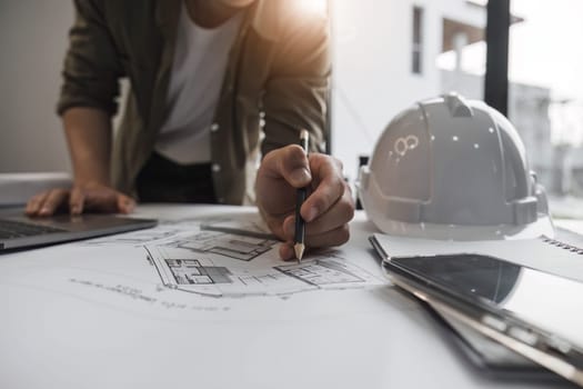 Engineers holding a pen pointing to a building and drawing outlay construction plan as guide for builders with details...