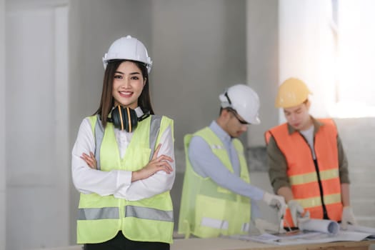 Civil engineer teams meeting working together wear worker helmets hardhat on construction site in modern city. Foreman industry project manager engineer teamwork. Asian industry professional team...